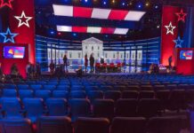 TV Debate Sparks Military Draft Fears Debate stage with red and blue lighting and empty audience seats
