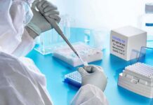Scientist in PPE using a pipette in a COVID-19 PCR testing setup