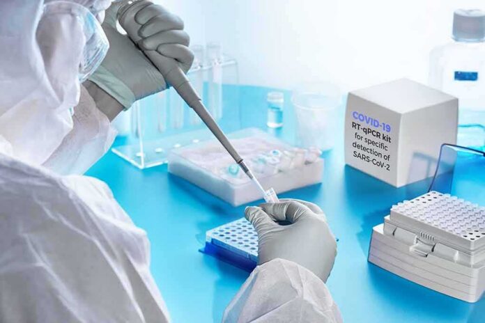 shutterstock_1676631628 Scientist in PPE using a pipette in a COVID-19 PCR testing setup
