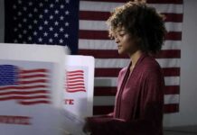 Gun Reference Fuels Political Firestorm Voter at a polling booth with an American flag backdrop