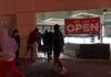People outside a storefront with broken glass at night