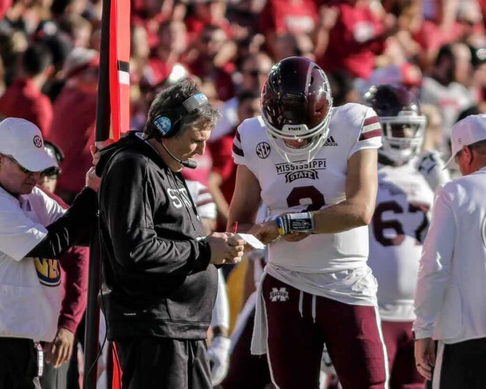 shutterstock_2070833297 Mississippi State football coach and quarterback review play card on sideline