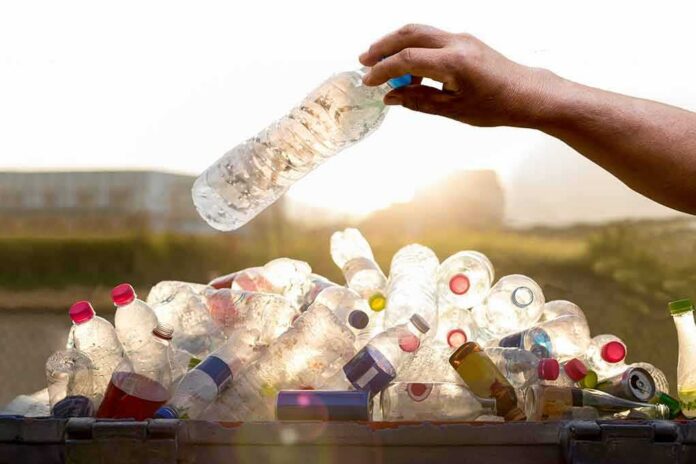 shutterstock_381535849 hand placing a plastic bottle into a bin of empty bottles