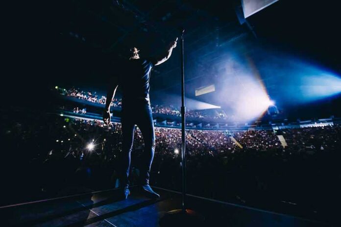shutterstock_568524262-1 Singer on stage facing a large concert crowd