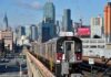 NYC subway 7 train on elevated tracks with city skyline