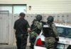 police officers in tactical gear beside patrol car