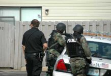 police officers in tactical gear beside patrol car