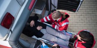 Paramedics load a patient on a stretcher into an ambulance